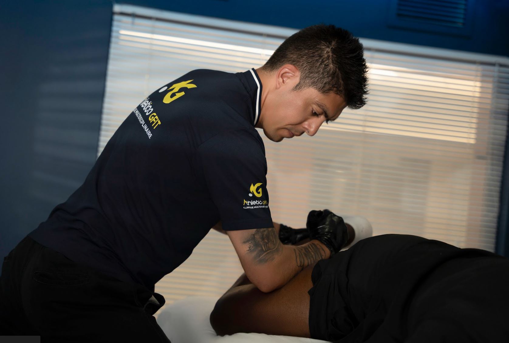 Thérapeute en polo Athletico GFIT guidant un étirement fascial assisté sur table